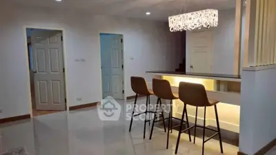 Modern interior with stylish bar stools and elegant lighting in a spacious living area.