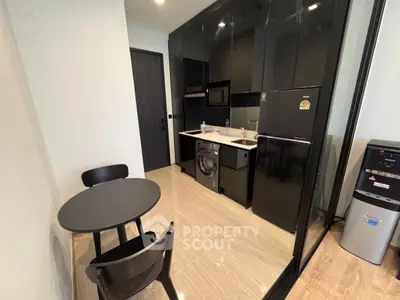 Modern compact kitchen with sleek black cabinets and integrated appliances