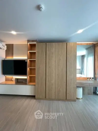 Modern living room with built-in wooden shelves and large TV