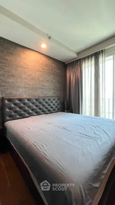 Spacious bedroom with modern decor and large window for natural light.