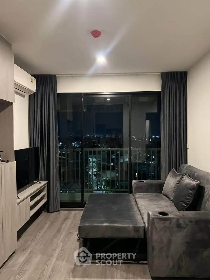 Modern living room with city view, featuring sleek furniture and floor-to-ceiling windows.
