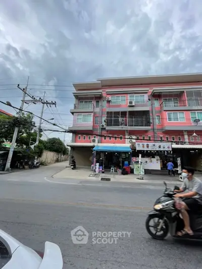 Vibrant pink building with commercial space on ground floor, ideal for business opportunities.
