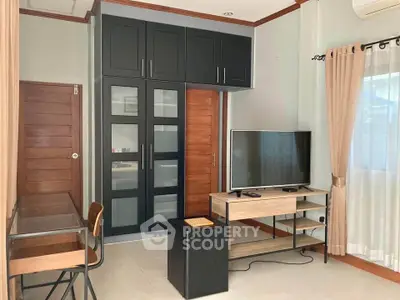Modern living room with sleek black cabinets and flat-screen TV, perfect for cozy relaxation.