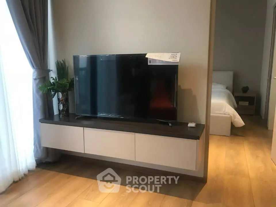 Modern living room with sleek TV setup and view into cozy bedroom