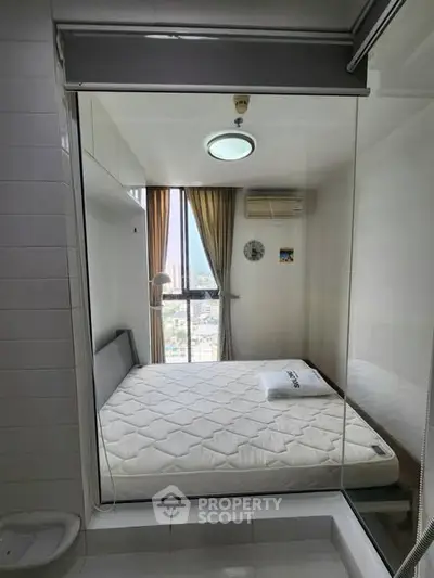 Compact bedroom with large window offering city view, featuring a cozy bed and modern air conditioning unit.