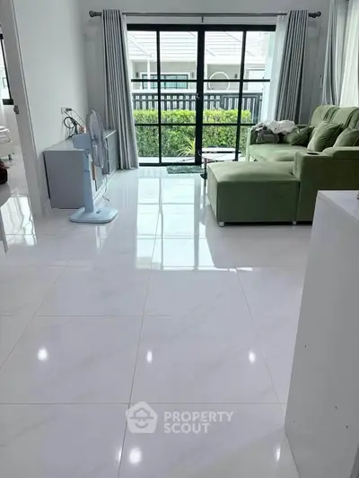 Bright living room with green sofa and balcony view, perfect for relaxation and comfort.