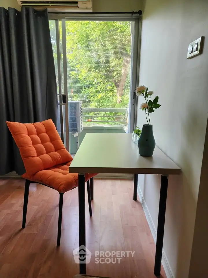 Bright study area with modern desk and orange chair, overlooking lush greenery through a large window.