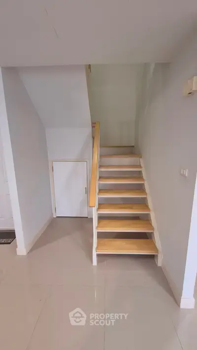 Modern staircase with light wood steps and sleek design in a contemporary home interior.