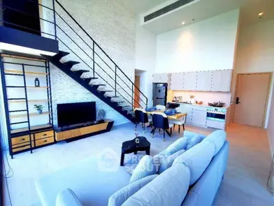 Modern loft-style living room with open kitchen and stylish staircase