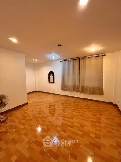 Spacious empty room with wooden flooring and curtains, ideal for customization.
