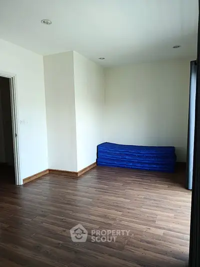 Spacious empty room with wooden flooring and natural light, ideal for customization.