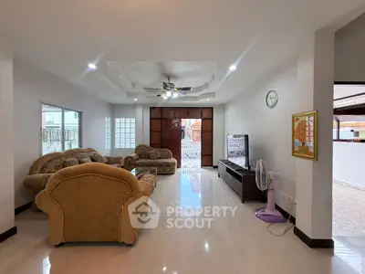 Spacious living room with elegant furniture and ceiling fan, perfect for family gatherings.