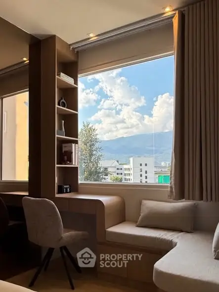 Modern living room with large window offering stunning mountain views, cozy seating, and stylish decor.