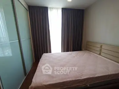 Cozy bedroom with large window and modern sliding wardrobe in a stylish apartment.