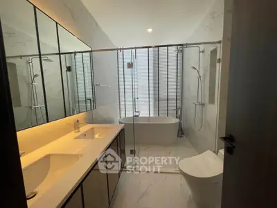 Luxurious modern bathroom with freestanding tub and dual sinks in elegant marble design.