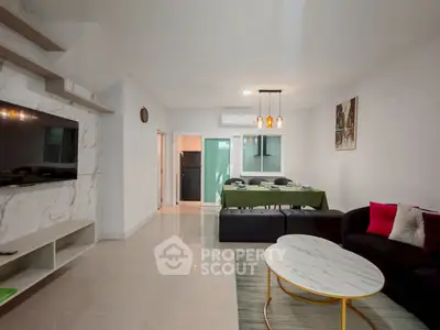 Modern living room with stylish decor and open dining area, featuring sleek furniture and elegant lighting.