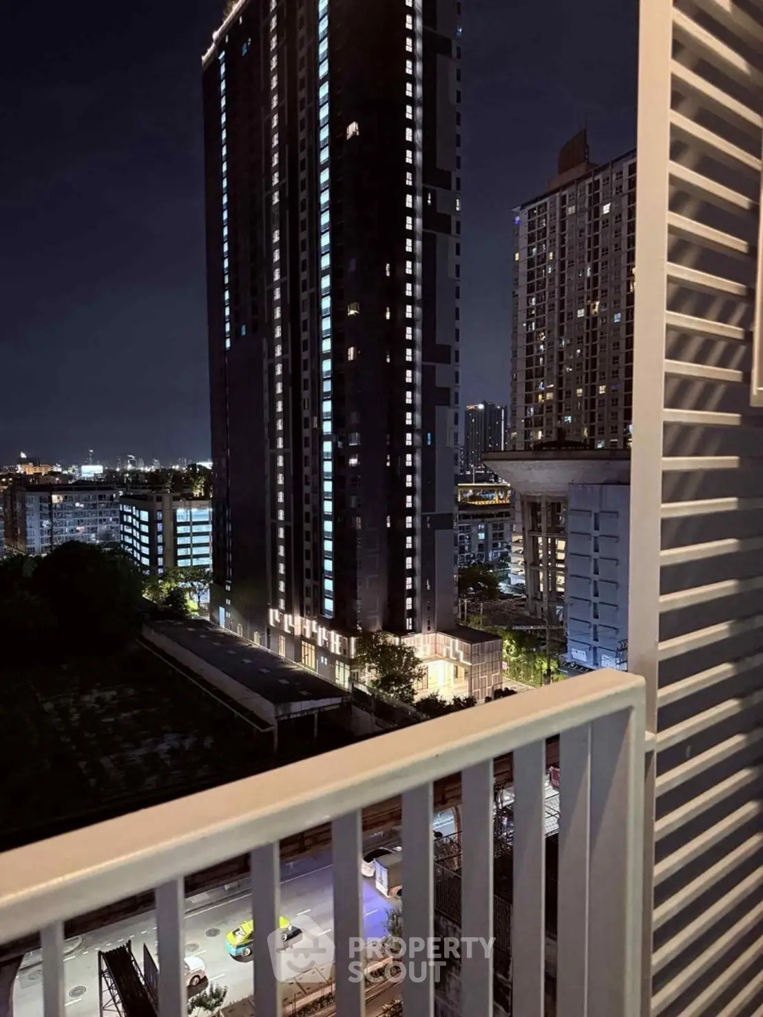 Stunning night cityscape view from a balcony overlooking modern high-rise buildings.