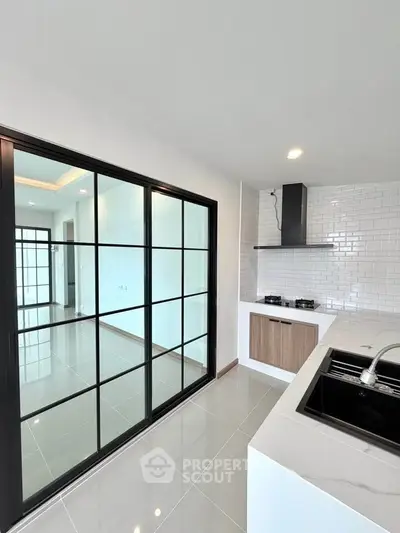 Modern kitchen with sleek design, featuring gas stove and stylish sliding glass doors.