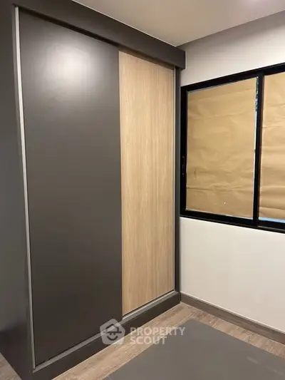 Modern bedroom with sleek sliding wardrobe and large window for natural light.