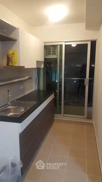 Modern kitchen with sleek cabinetry and balcony view in urban apartment
