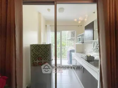 Modern kitchen with balcony view, sleek cabinets, and natural light.