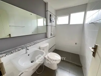 Modern bathroom with sleek fixtures and large mirror in a bright, tiled space.