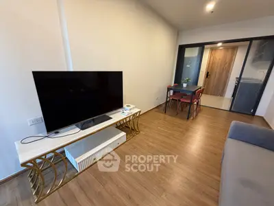 Modern living room with sleek TV stand and dining area in open layout apartment.