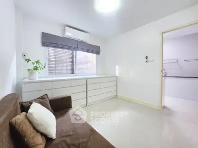 Bright and cozy living room with modern sofa and ample natural light, perfect for relaxation.