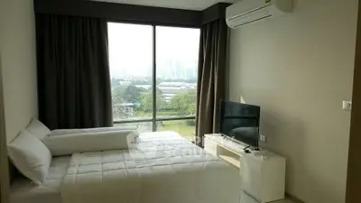 Modern bedroom with large window and city view, featuring a cozy bed and TV.