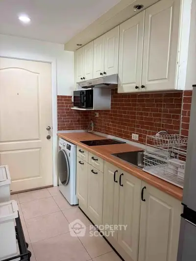 Charming kitchen with brick backsplash, modern appliances, and ample cabinetry in cozy apartment.