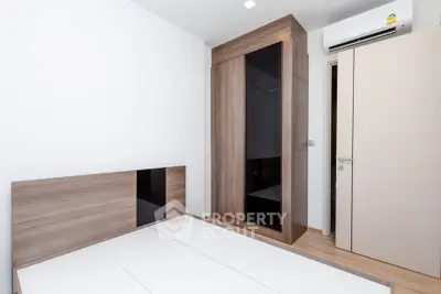 Modern minimalist bedroom with sleek wooden furniture and air conditioning unit.