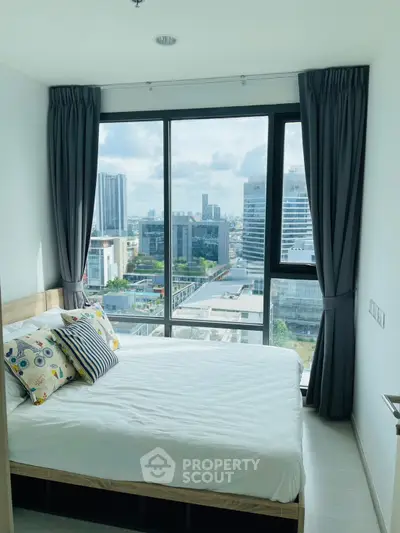 Modern bedroom with large windows offering stunning city views in a high-rise apartment.