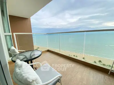 Stunning beachfront balcony with panoramic ocean views and cozy seating area.