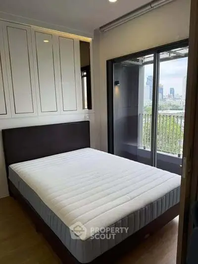 Modern bedroom with city view and balcony access in a stylish apartment.