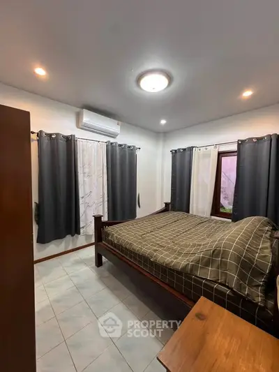 Cozy bedroom with modern lighting and air conditioning, featuring a comfortable bed and stylish curtains.