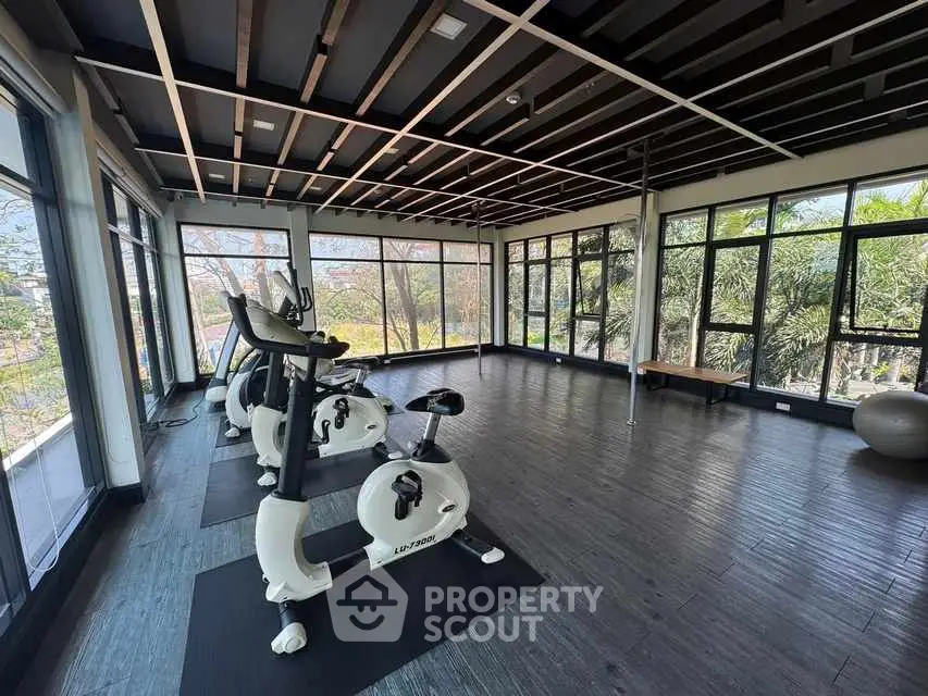 Spacious gym with modern exercise equipment and large windows offering scenic views.