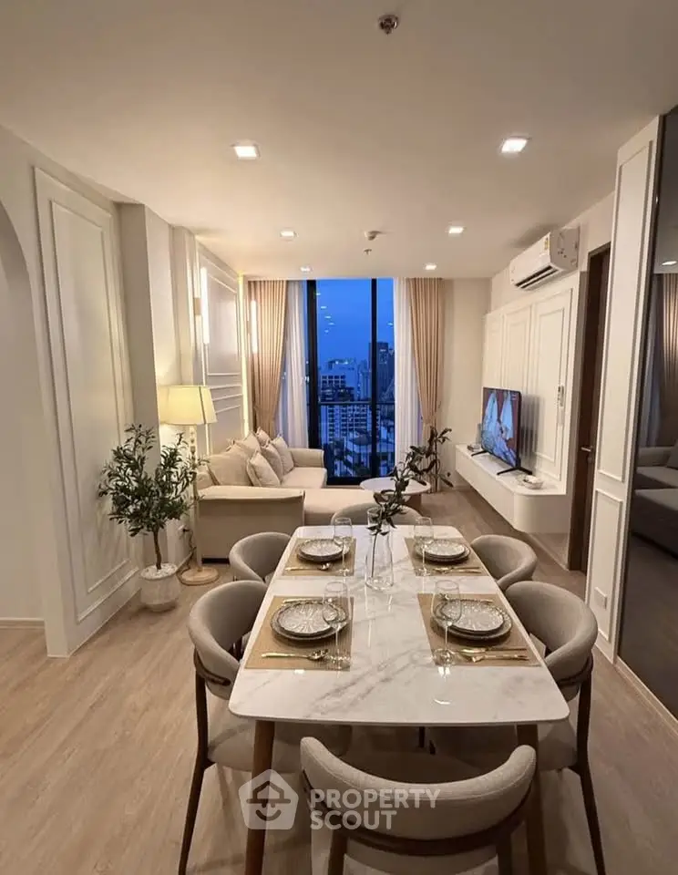Elegant living room with dining area and city view, featuring modern decor and ambient lighting.