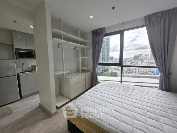 Modern bedroom with city view, featuring open shelving and large windows for natural light.