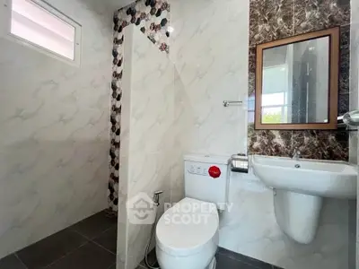 Modern bathroom with stylish tiles and sleek fixtures, featuring a toilet and sink.