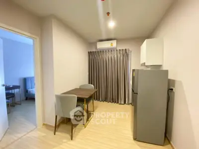 Modern dining area with sleek table and chairs, adjacent to a compact kitchen with fridge and air conditioning.