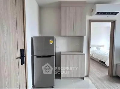 Modern kitchen with sleek fridge and wooden cabinets in stylish apartment.
