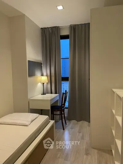 Cozy bedroom with modern decor, featuring a bed, desk, and city view through large window.