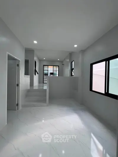 Spacious modern interior with sleek white flooring and ample natural light, perfect for contemporary living.