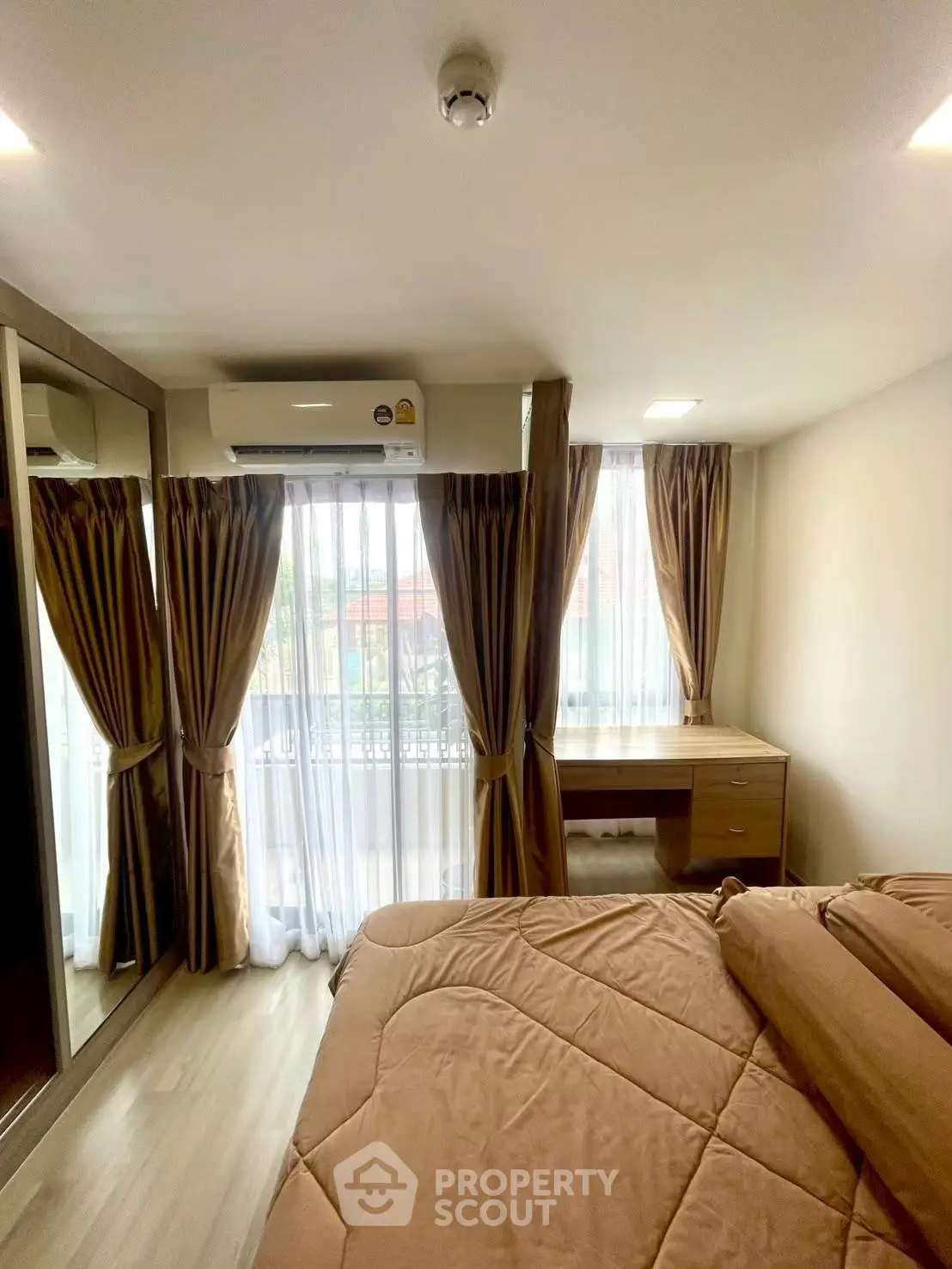 Cozy bedroom with large window, elegant curtains, and a mirrored wardrobe in a modern apartment.