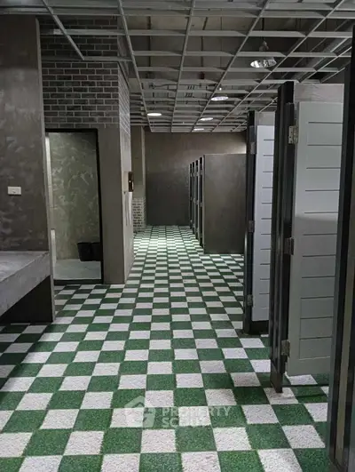 Modern public restroom with stylish green and white checkered flooring and sleek partitions.