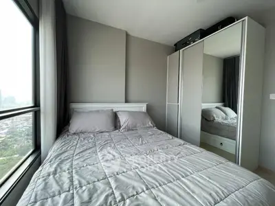 Modern bedroom with large window and mirrored wardrobe offering city views.