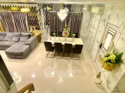 Luxurious living room with elegant dining area and plush sofa, featuring modern decor and chandelier lighting.