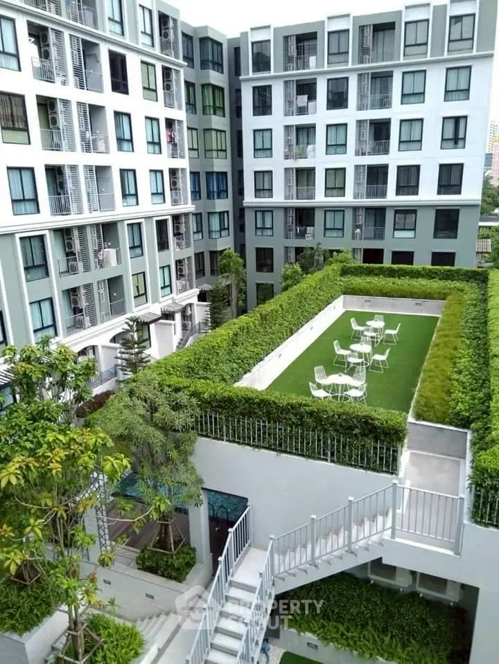 Modern apartment building with lush green rooftop garden and seating area.