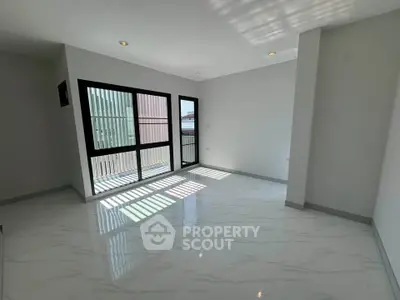 Spacious modern living room with large windows and glossy tiled floor, perfect for natural light lovers.