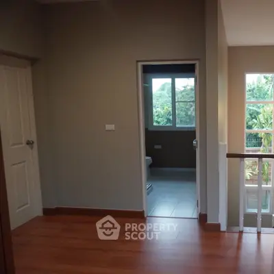 Spacious hallway with wooden flooring and view into a bright bathroom.